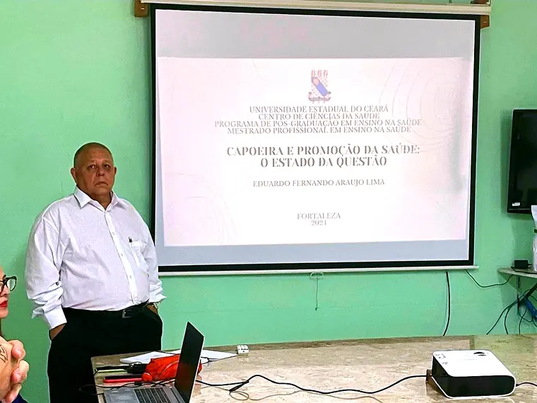 Mestre Dunga apresentando slide sobre capoeira e promoção da saúde