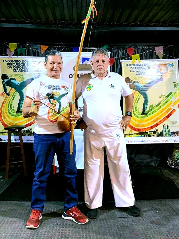 Mestre Dunga segurando um arco decorado em evento de capoeira