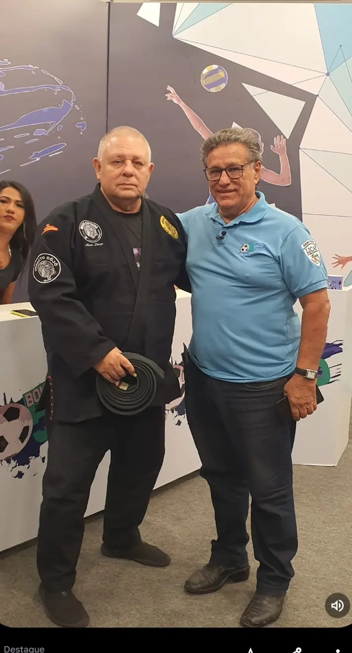 Mestre Dunga de kimono preto ao lado de um parceiro de polo azul