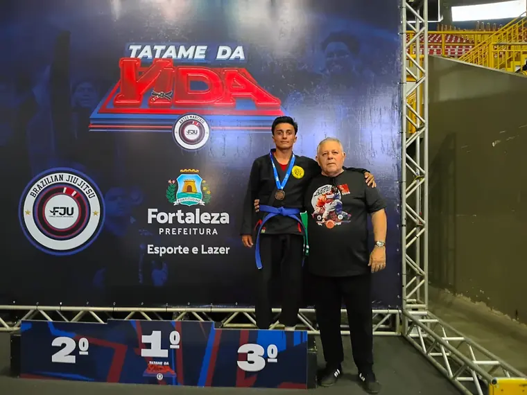 Aluno no pódio do Tatame da Vida com medalhas de 1º, 2º e 3º lugar