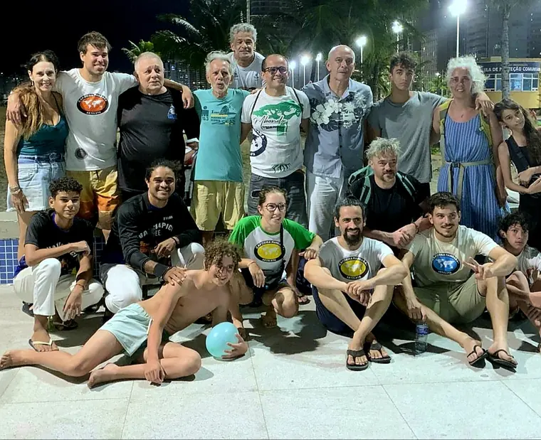 Grande grupo de capoeiristas reunido à noite na praia