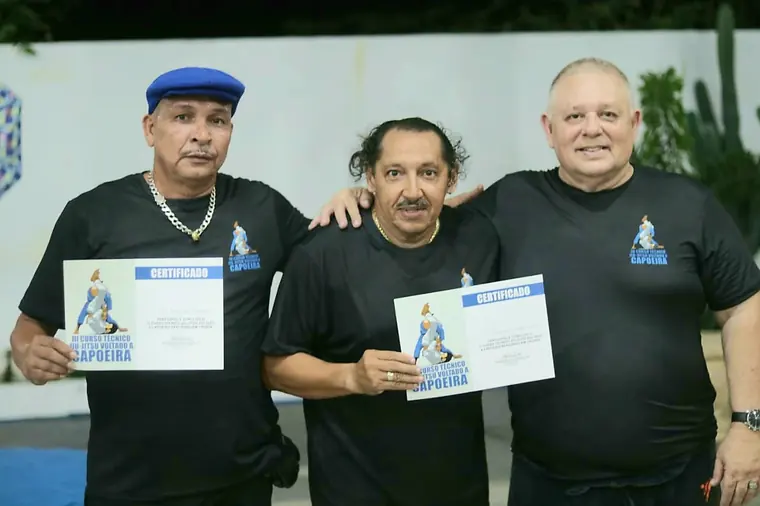 Três mestres de boné posando com certificados nas mãos